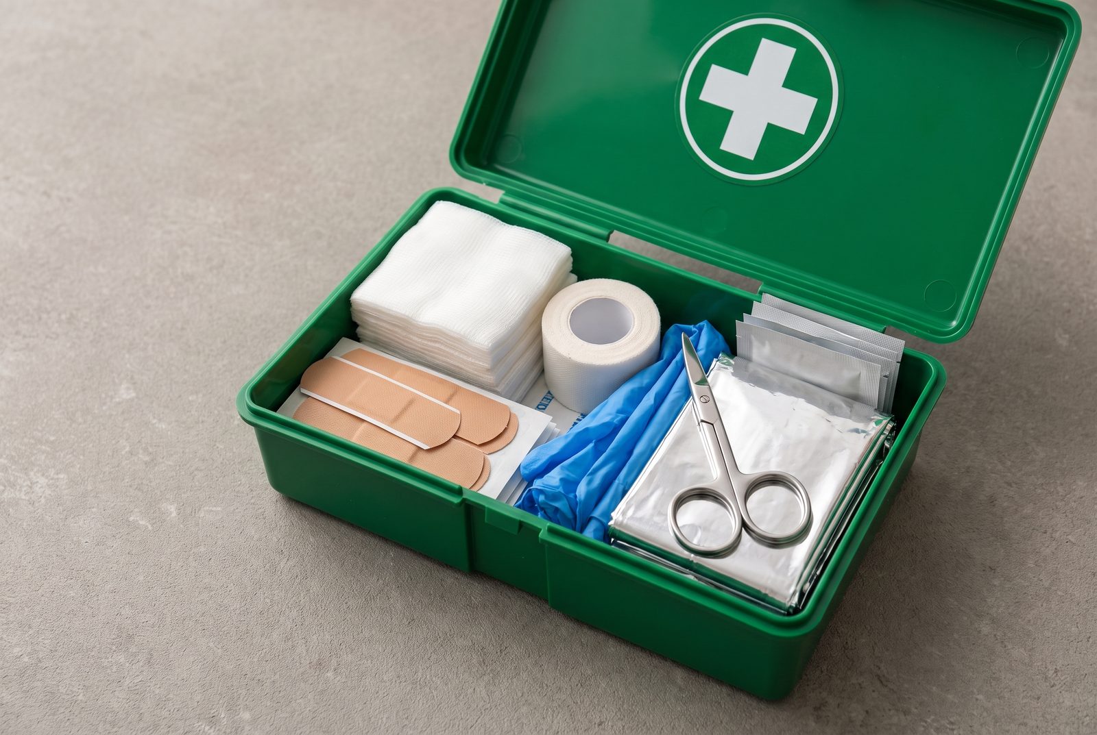Open workplace first aid kit with bandages, tape, gloves and emergency supplies